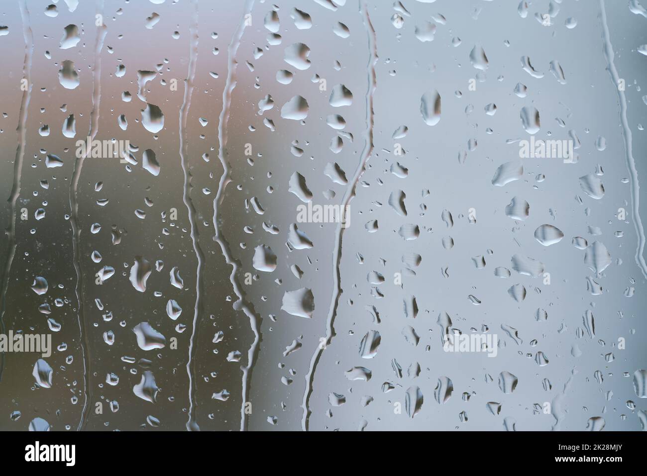 Regentropfen auf einer Fensterscheibe bei regnerischem Wetter Stockfoto