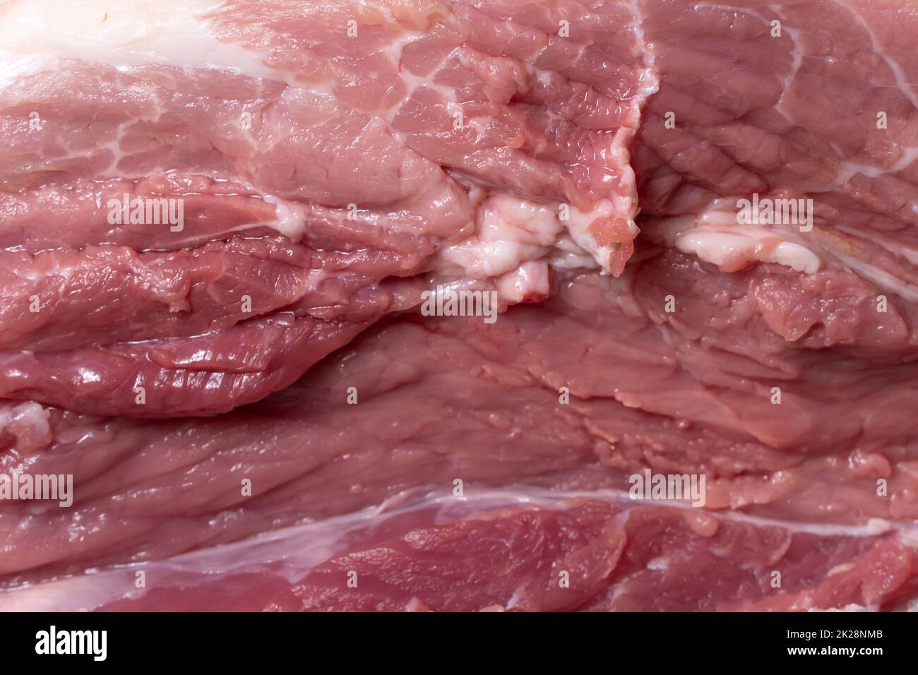 Schneiden Sie das Schweinefleisch oder Rindfleisch mit einem Messer auf dem Tisch in Nahaufnahme. Zubereitung von Fleischgerichten und Nahrungsmitteln. Stücke von rotem Fleisch für Shish Kebab, Barbecue oder Kebab. Rohes frisches Fleisch. Rezept Stockfoto