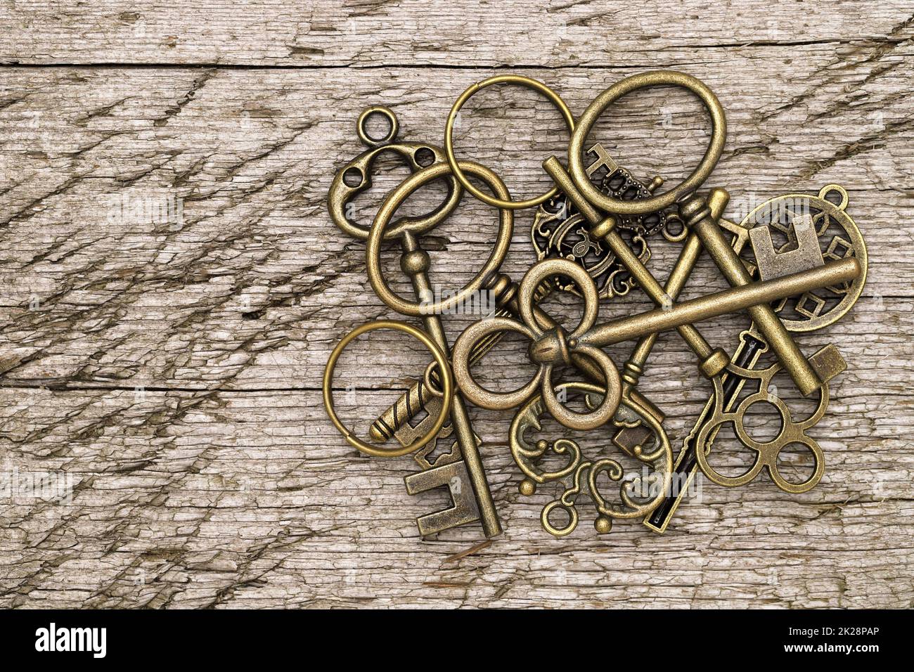 Stapel goldener Vintage-Schlüssel auf grungigem Holzhintergrund Stockfoto