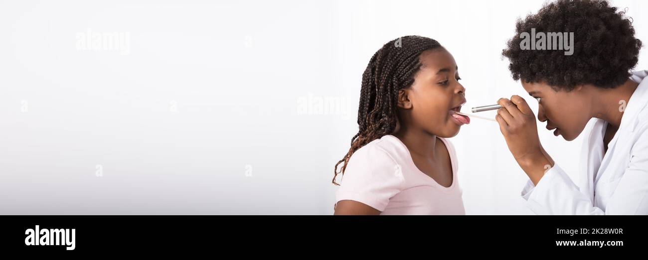Afroamerikanischer Arzt, Der Die Kehle Des Kindes Auf Grippe Überprüft Stockfoto
