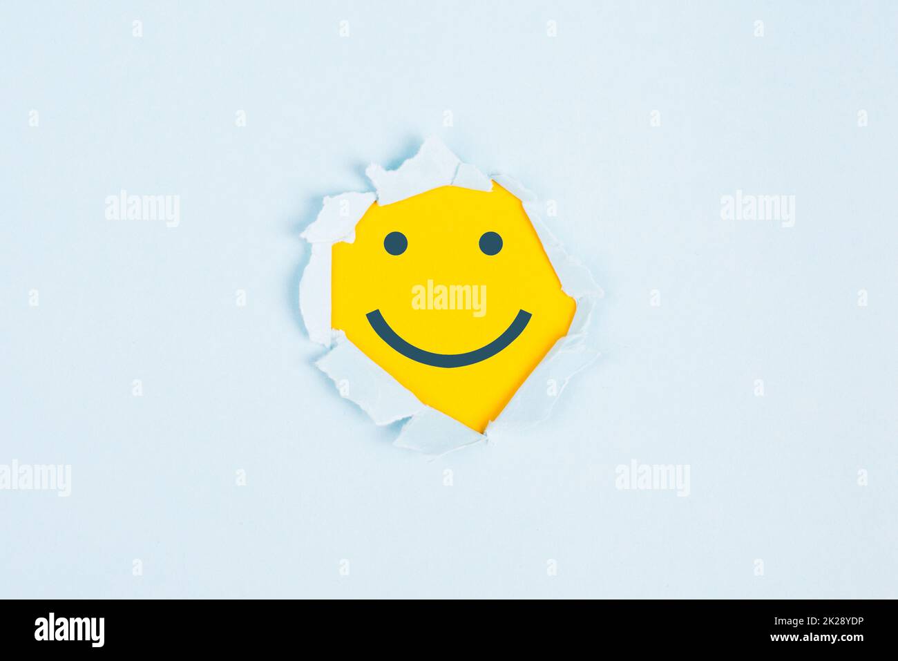 Lächelndes, glückliches Gesicht unter einem zerrissenen Papier, positive Emotionen, gutes Kundenfeedback, Lachen Stockfoto