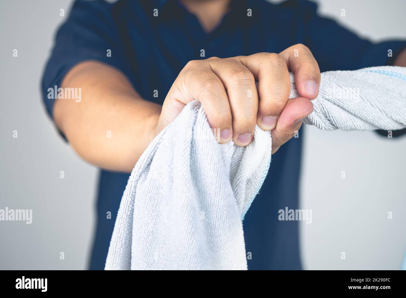 Der Mann dreht das Handtuch zur Massage und macht Physiotherapie am Arm. Ellenbogenverletzungen durch Tennis, Golf, harte Arbeit. Wissen im Gesundheitswesen. Mittlere Nahaufnahme. Stockfoto