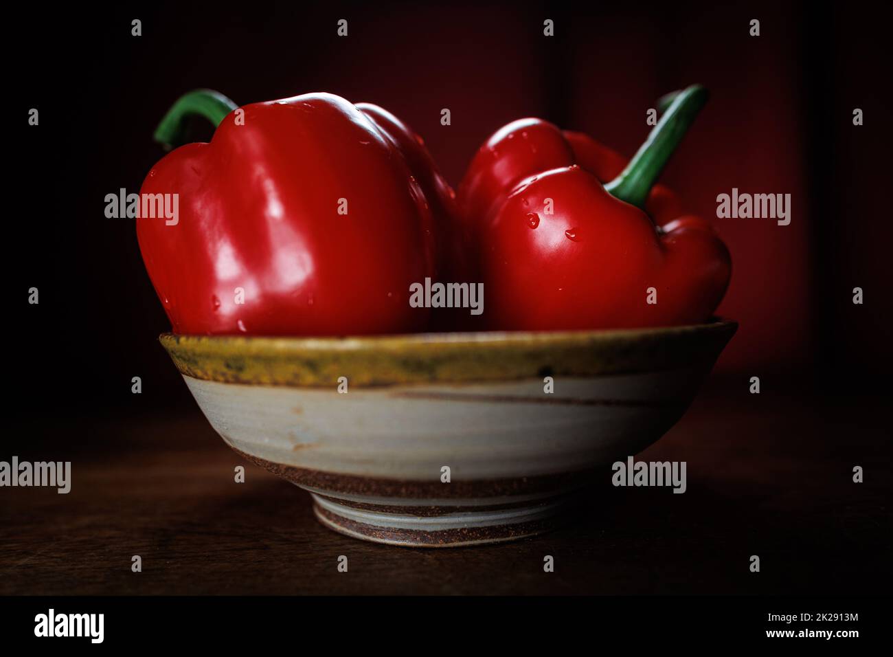 Zwei rote Paprika in einer Schüssel mit rotem Hintergrund Stockfoto