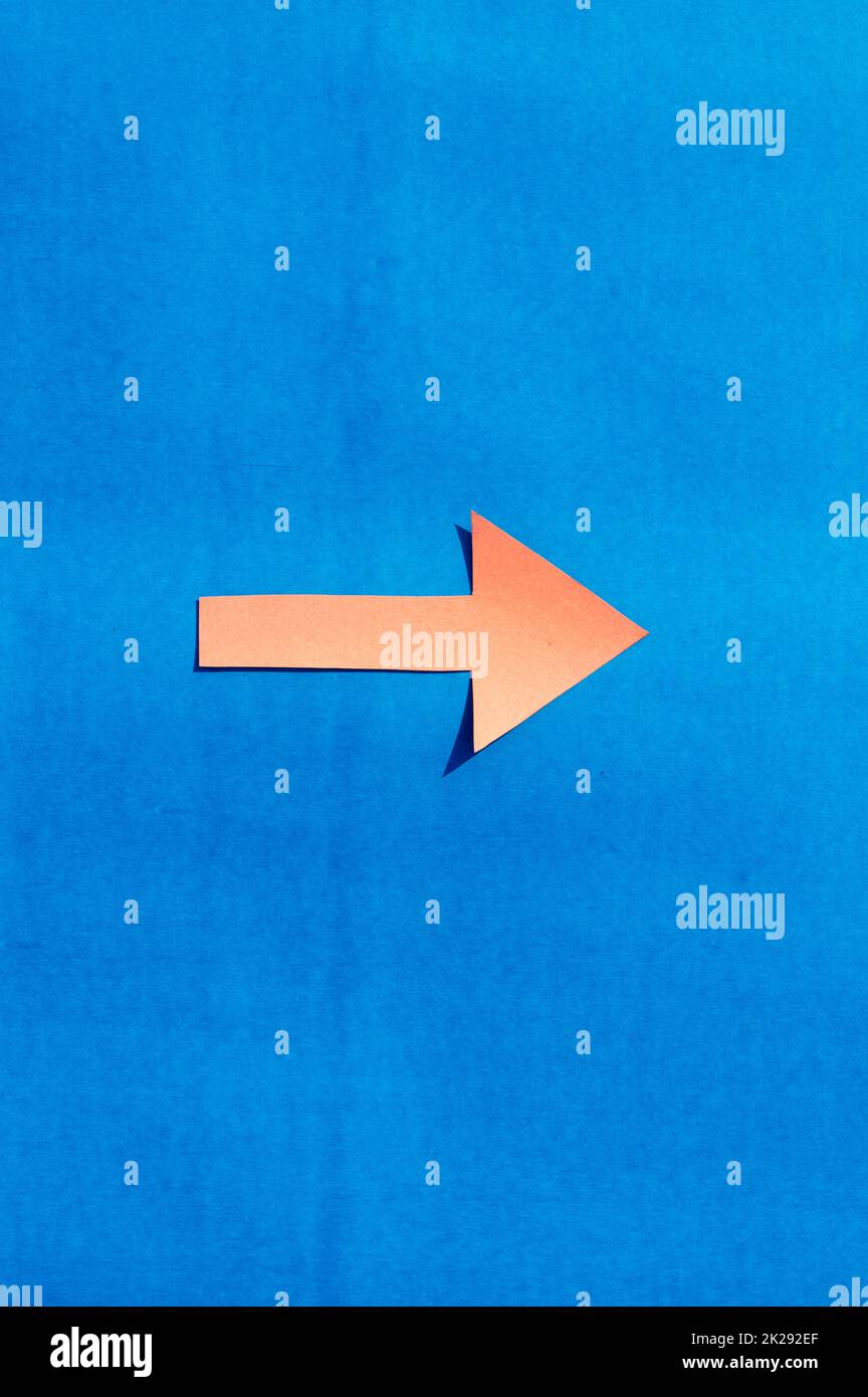 Ein nach rechts zeigender Pfeil, der die richtige Richtung angibt. Isoliert auf blauem Hintergrund. Nützlich für Beschilderung und für Wegweiser und Oberflächenmarkierungen. Stockfoto
