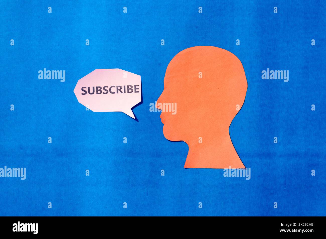 Papier menschliches Gesicht mit Wort auf Sprechblase abonnieren isoliert auf blauem Hintergrund. Platz für Text kopieren. Stockfoto