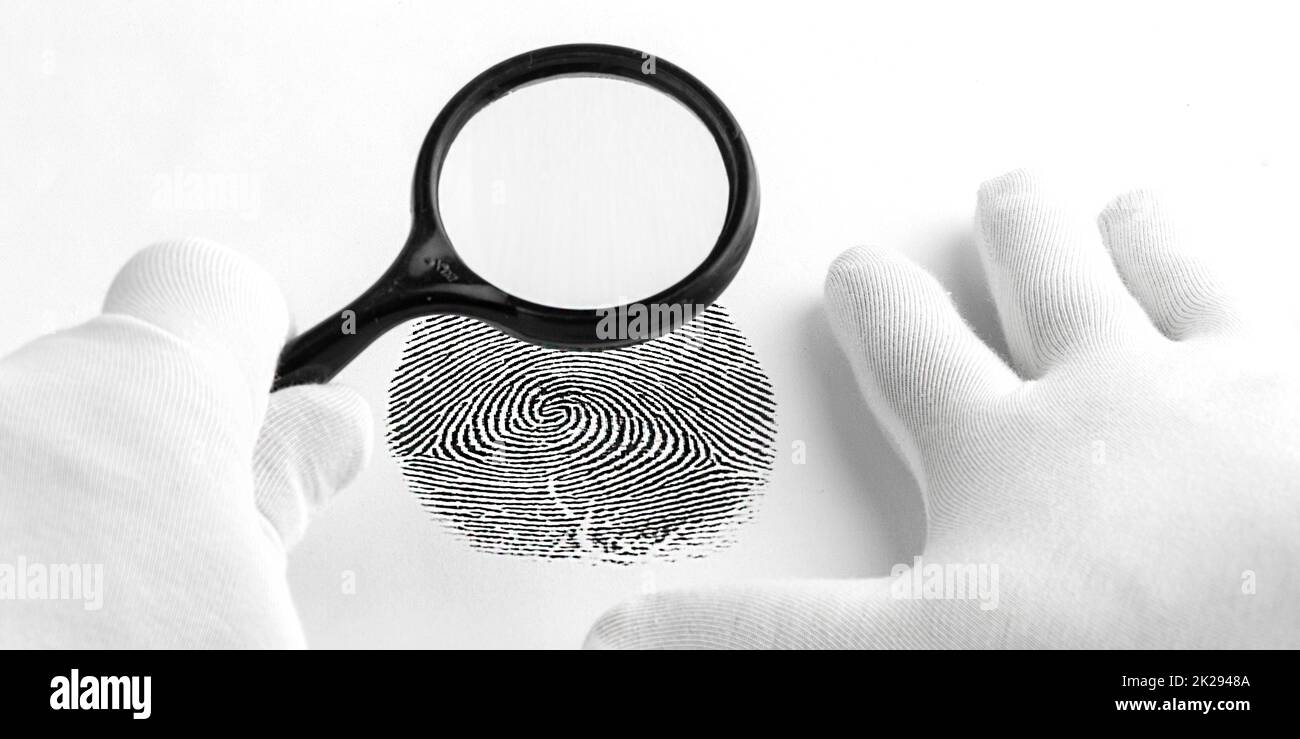 Kriminologieexperte durch eine Lupe, die auf einen Fingerabdruck schaut. Stockfoto