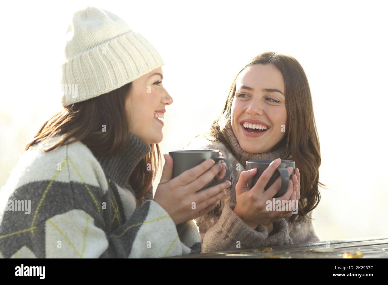 Glückliche Freunde, die im Winter in einem Park trinken und reden Stockfoto