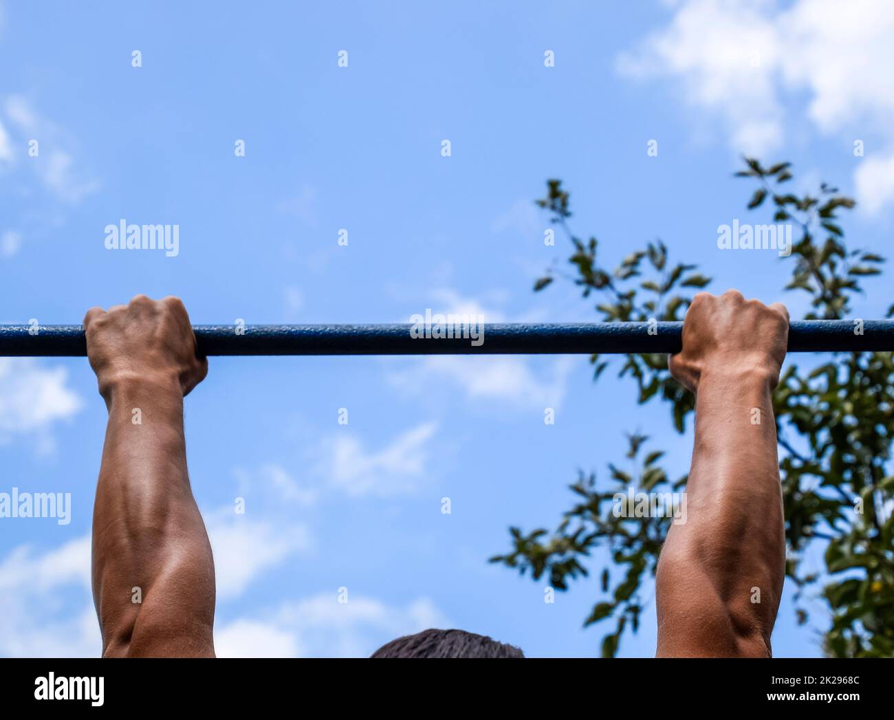 Hände auf die Bar zu schließen. Der Mann zieht sich an der Bar. Sport an der frischen Luft. Horizontale Leiste. Stockfoto