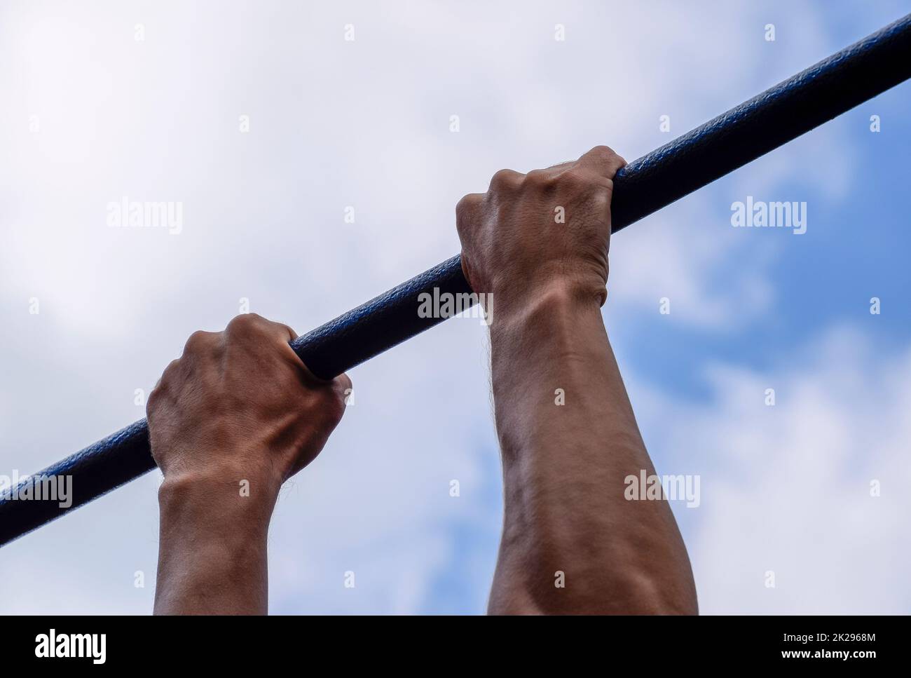 Hände auf die Bar zu schließen. Der Mann zieht sich an der Bar. Sport an der frischen Luft. Horizontale Leiste. Stockfoto