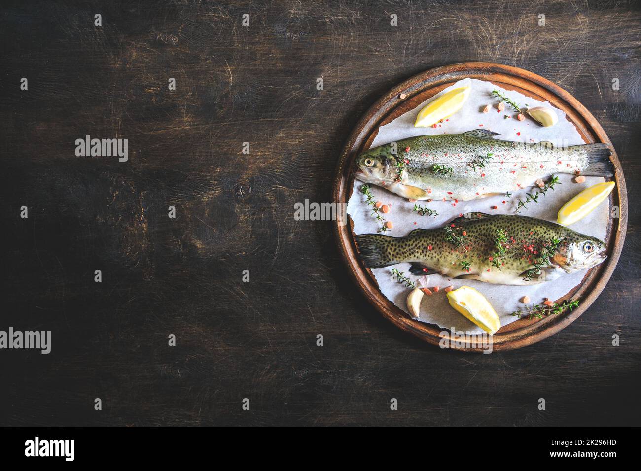 Zwei rohe Regenbogenforellen auf Papier mit Thymian und Zitrone. Fischforelle. Draufsicht. Geben Sie Platz für Ihren Text. Stockfoto