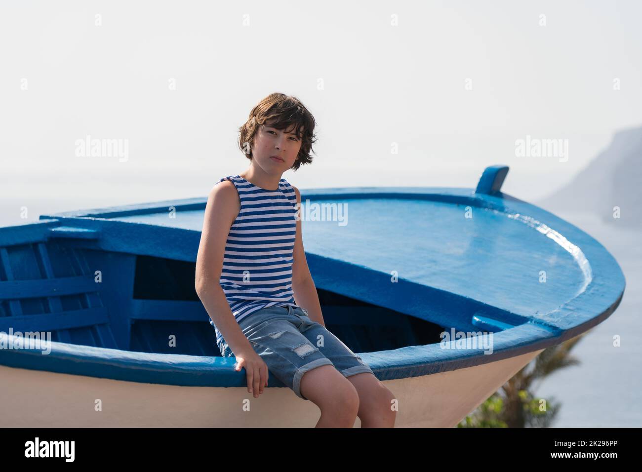 Porträt eines Teenagers, der auf einem Holzboot sitzt. Stockfoto