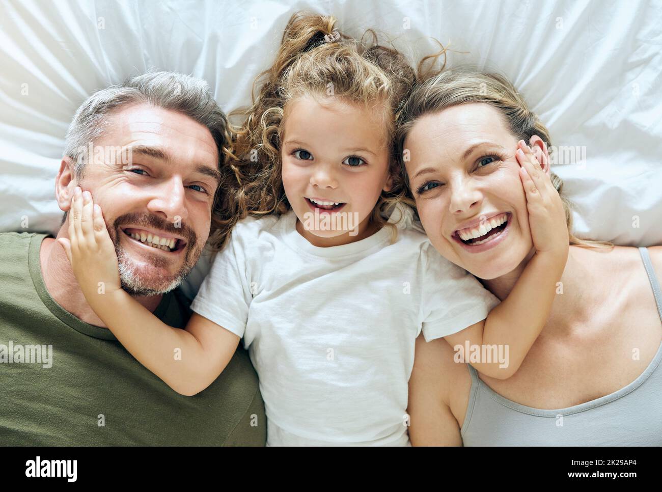 Porträt von Familie zu Hause, Mädchen und Eltern auf dem Bett für Spaß am Morgen, entspannen Sie Lebensstil und Glück. Oben von lächeln Mama, glücklichen Vater und verspielte Kind Stockfoto