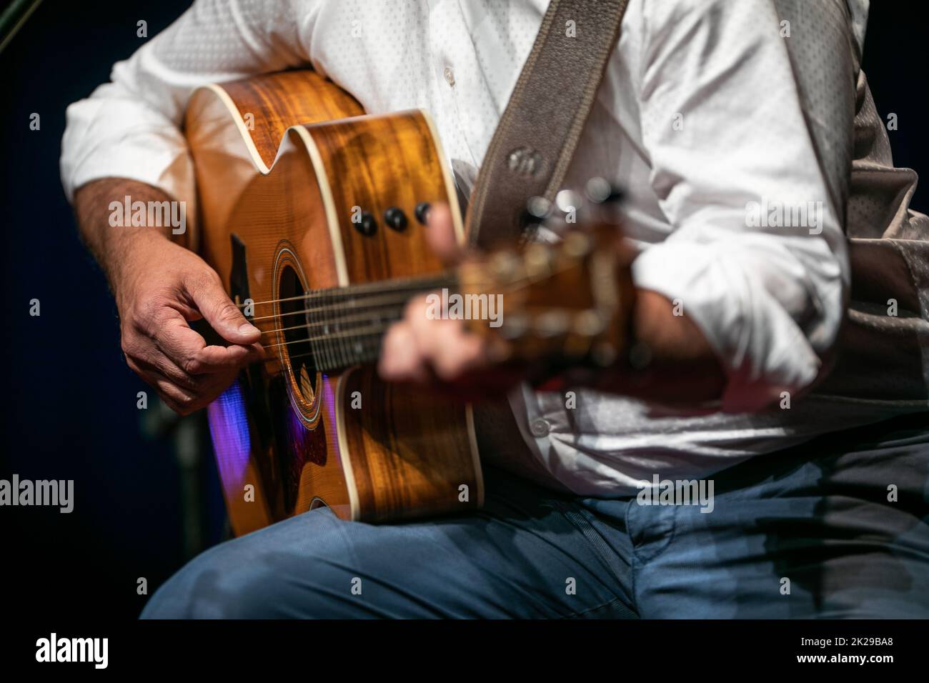 Mann, der auf der Bühne eine Gitarre spielt (flaches, farbiges Bild des Freiheitsgrads) Stockfoto