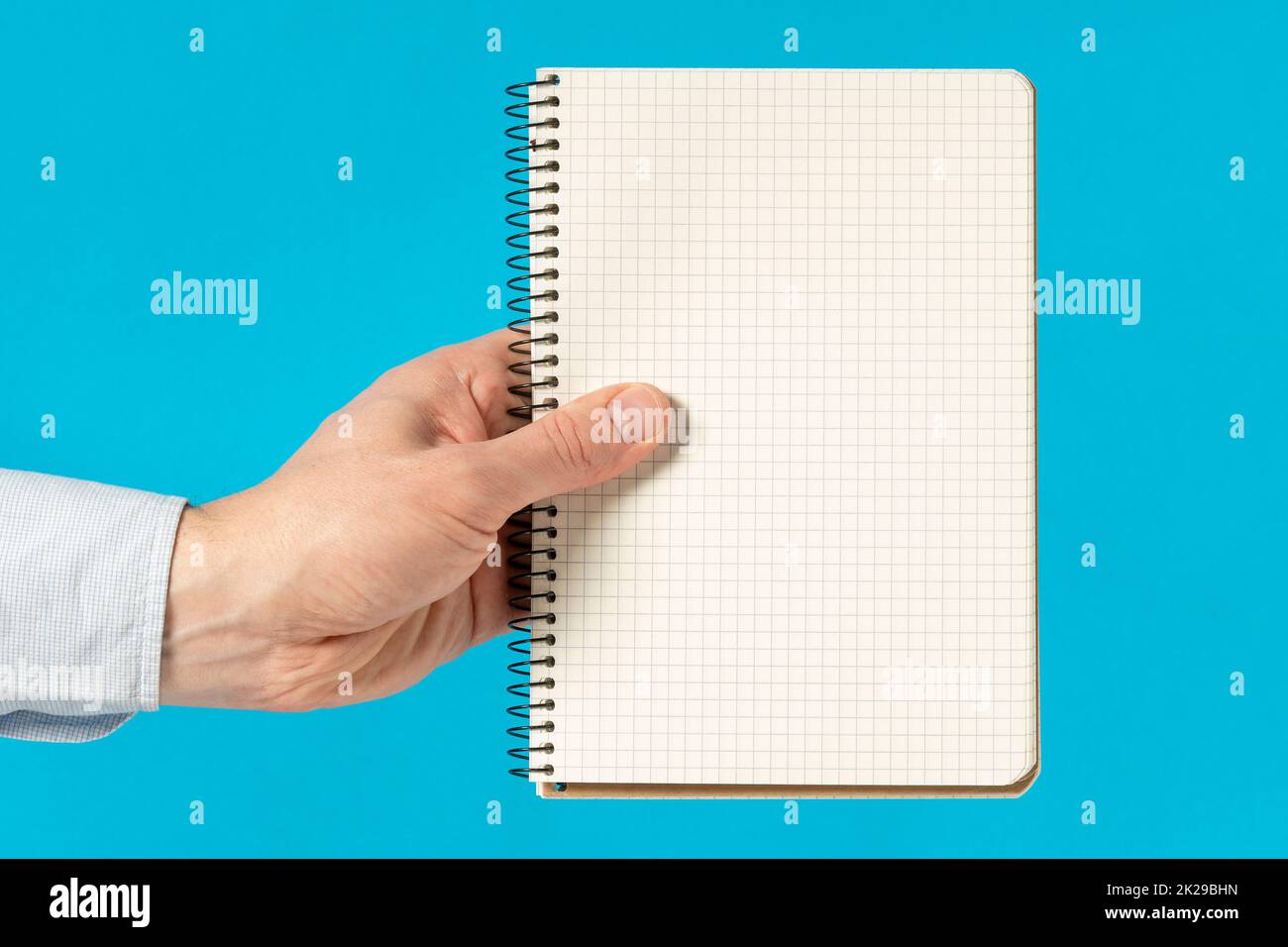 Man Hand hält ein Notizbuch mit quadratischem Raster Stockfoto