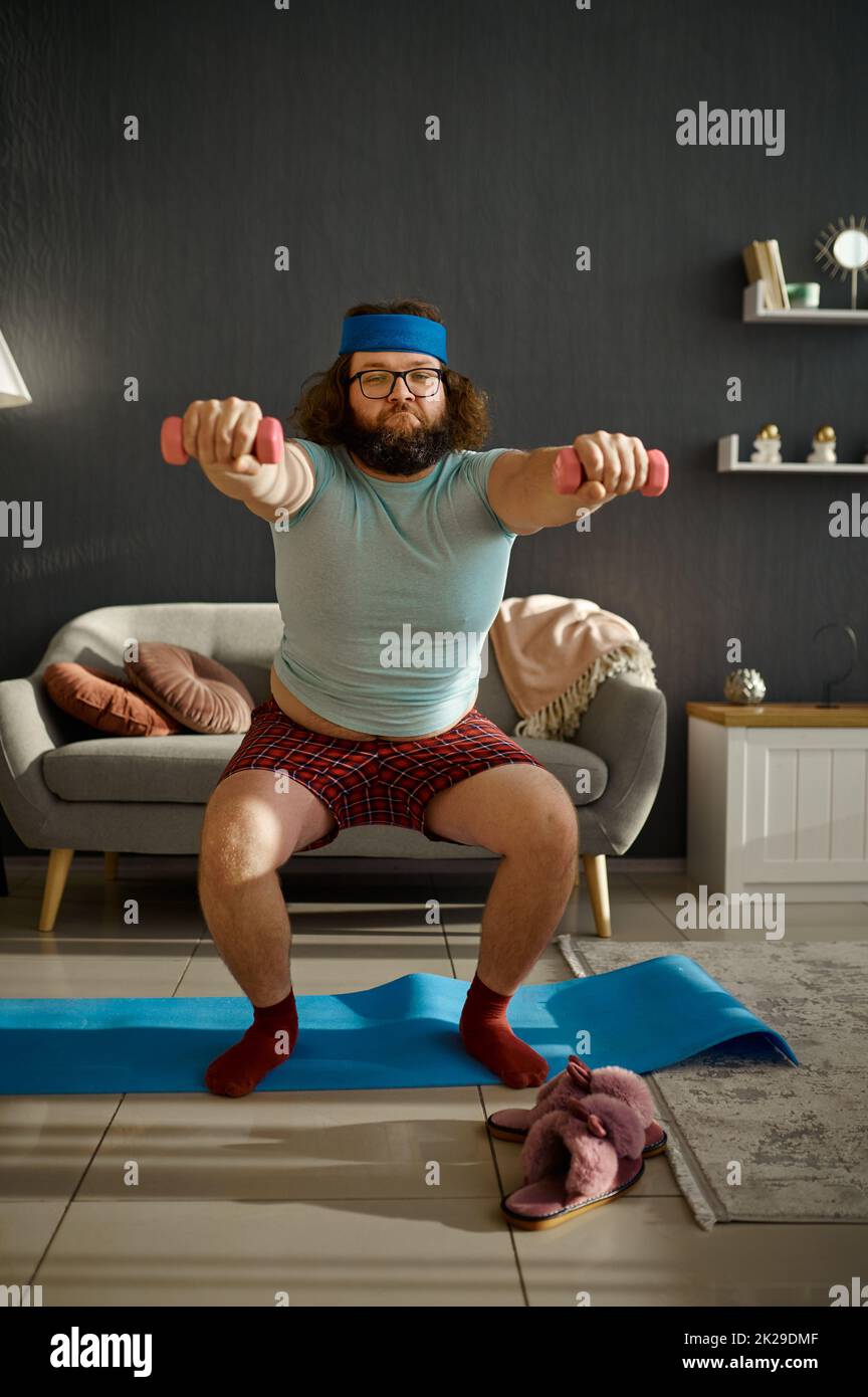 Lustiger Mann beim morgendlichen Training mit Hanteln Stockfoto