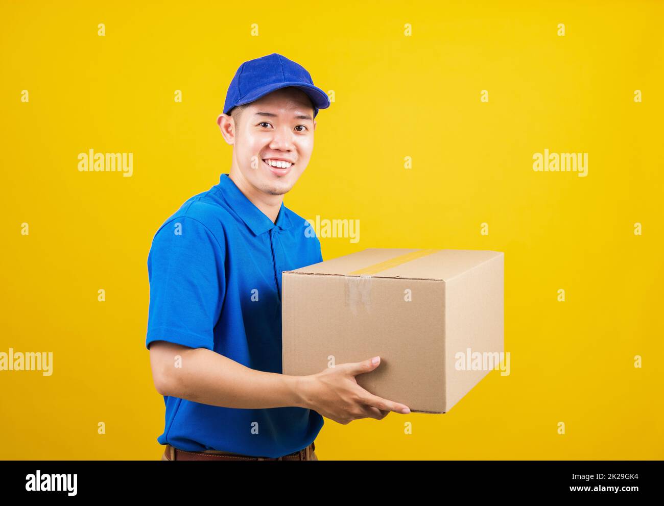 Lieferung glücklicher Mann logistisch stehend lächelt er trägt ein blaues T-Shirt und eine Kappe Uniform Paketkiste Stockfoto
