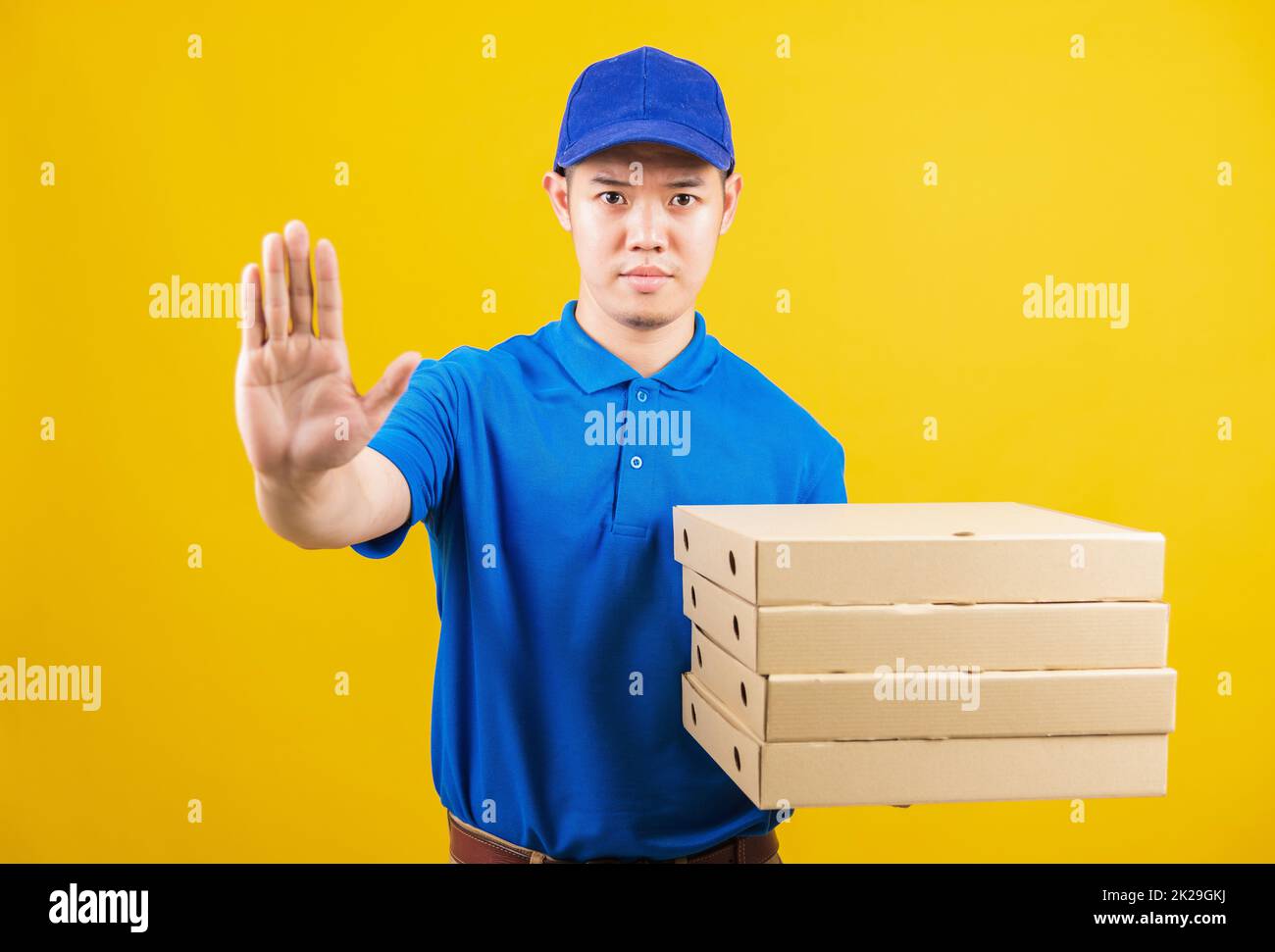 Lieferservice Mann mit blauem T-Shirt und Kappe Uniform halten Papierkiste italienische Pizzapackung und zeigen Hand-Stopp-Zeichen-Geste Stockfoto
