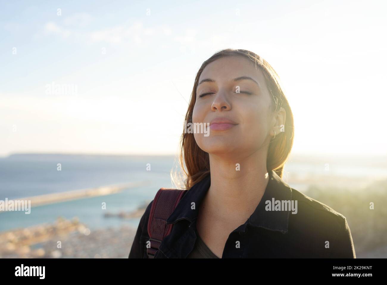 Schöne junge Frau mit geschlossenen Augen atmen entspannend genießen Sonne bei Sonnenuntergang. Schönheit Sonnenschein Mädchen Porträt. Stockfoto