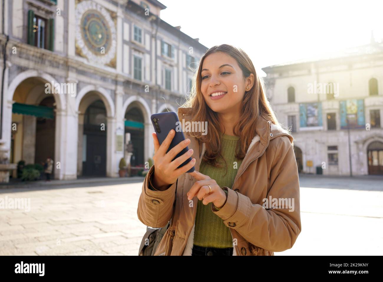 Schönes Mädchen chattet mit ihrem Smartphone an sonnigen Tag in der Altstadt in Europa Stockfoto