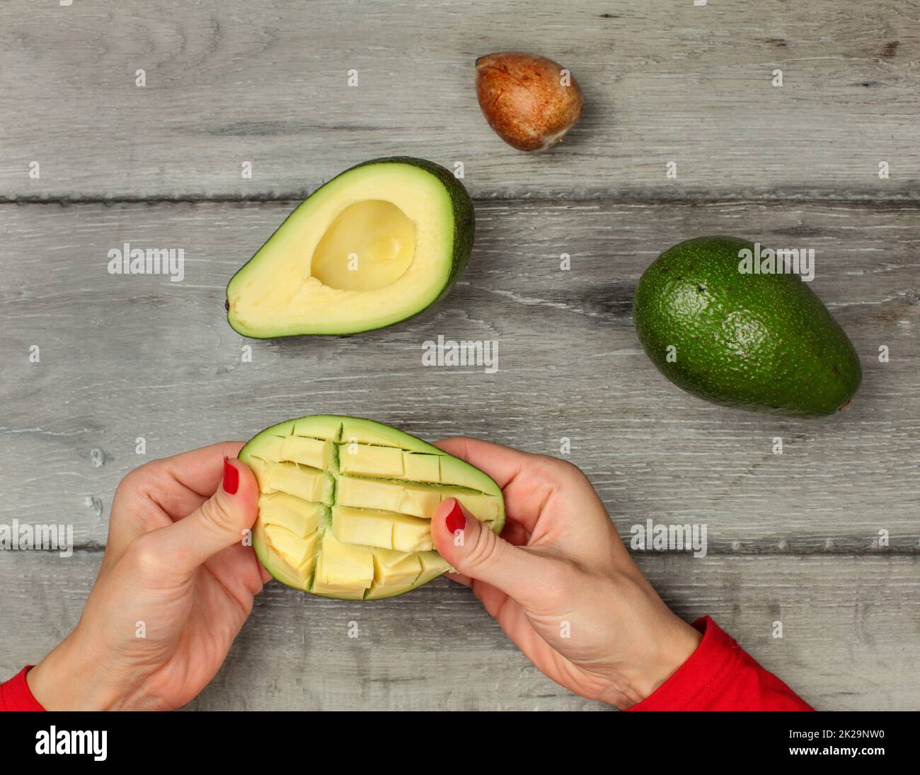 Tischplatte Blick auf Frau Hände vorbereiten, Avocado, aus dem Fruchtfleisch schneiden in den Quadraten. Stockfoto