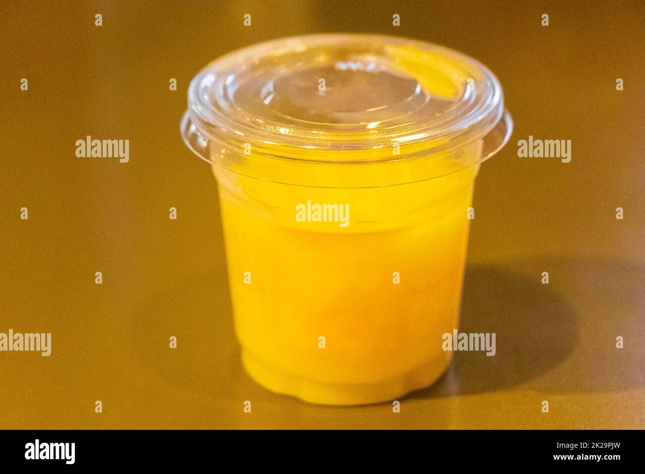 Kunststoffbehälter mit gelbem Flüssigsaft ohne Logo zur Beschriftung. Stockfoto