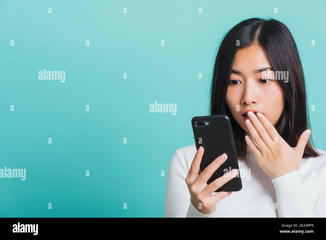 Frau überrascht schockiert mit Handy schließen Mund mit Handfläche Stockfoto