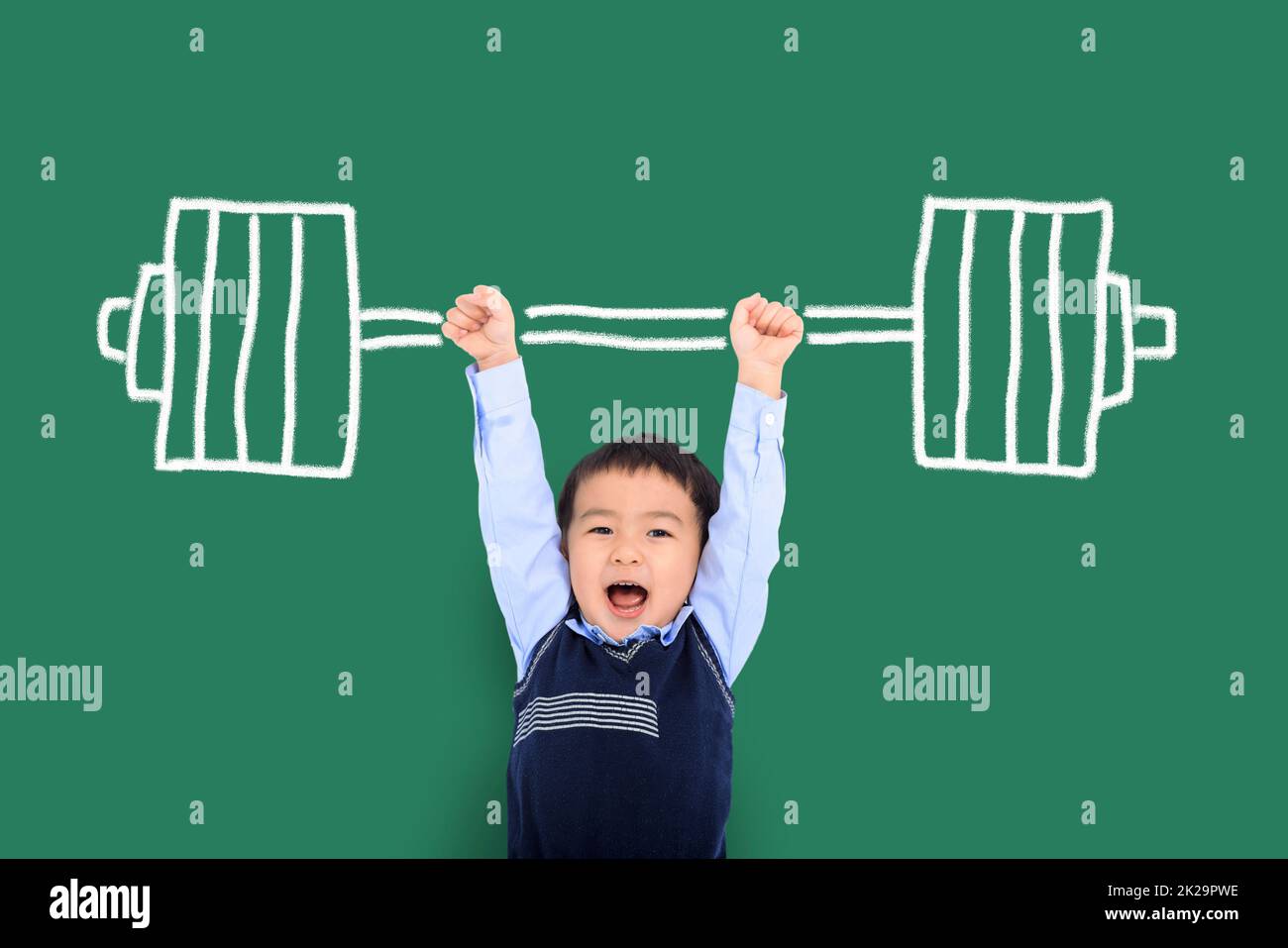 Glücklicher Junge, der mit hochgezogene Arme steht und die Hanteln hält Stockfoto