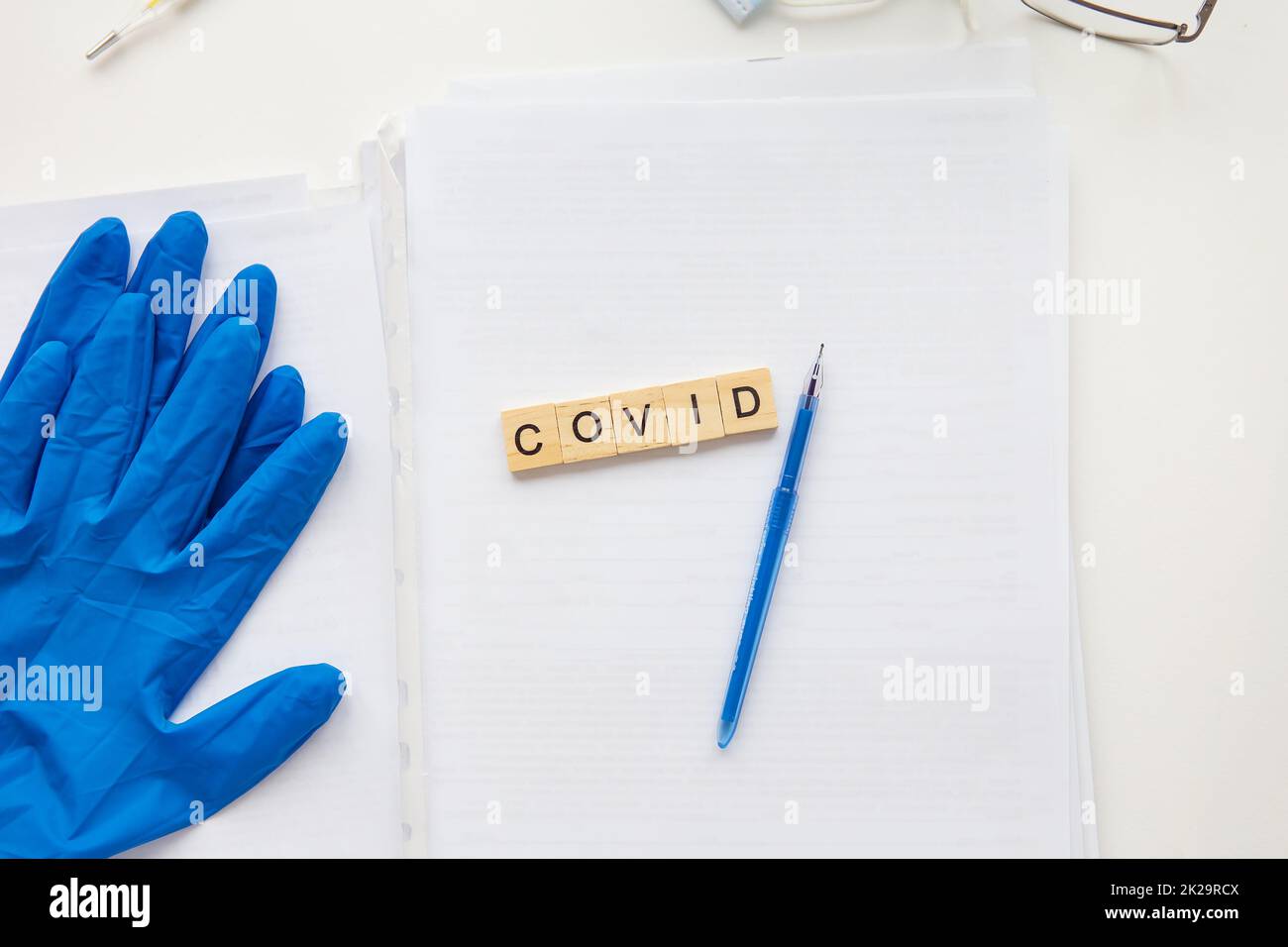 Die Inschrift auf einem medizinischen Hintergrund, neben Handschuhen, einem Stift, einer Brille und Papieren mit Patientendaten. Medizinisches Thema. Konzept: Impfung gegen Coronavirus. Stockfoto