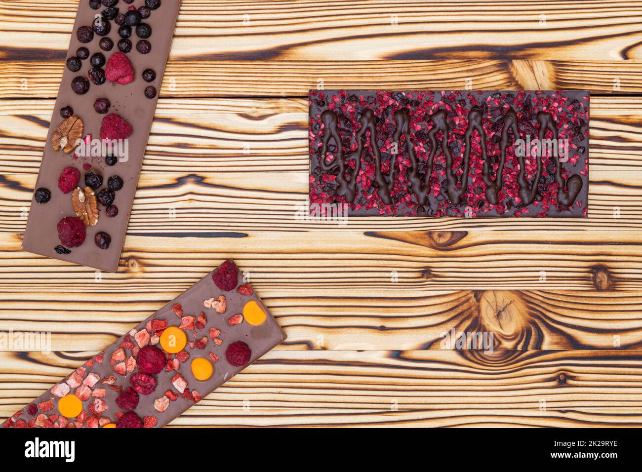 Verschiedene Arten von Schokolade mit getrockneten Früchten auf einem Holzbrett Stockfoto
