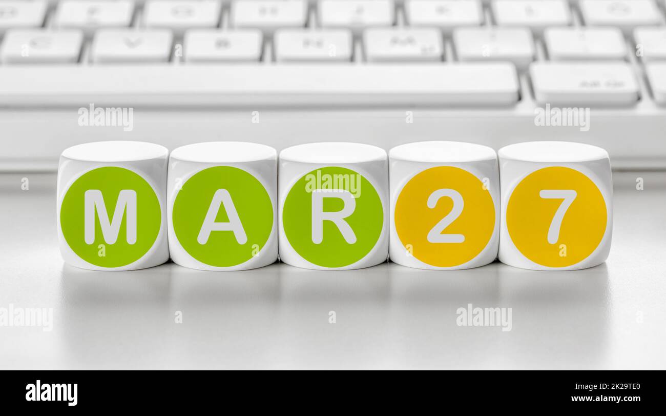 Buchstabenwürfel vor einer Tastatur - 27. März Stockfoto