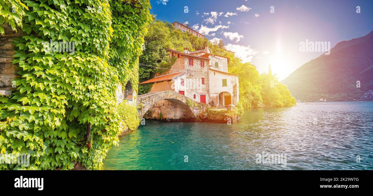 Die historische Steinbrücke der Stadt Nesso und der malerische Panoramablick am Seeufer mit Sonnenschein Stockfoto