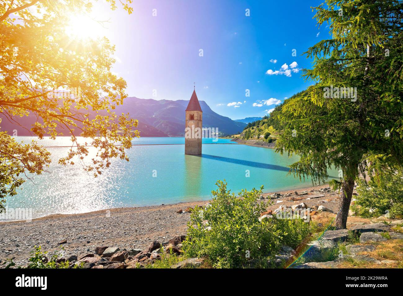 Untergetauchter Glockenturm von Curon Venosta oder Graun im Vinschgau auf dem Reschen-See mit Blick auf die Sonne Stockfoto