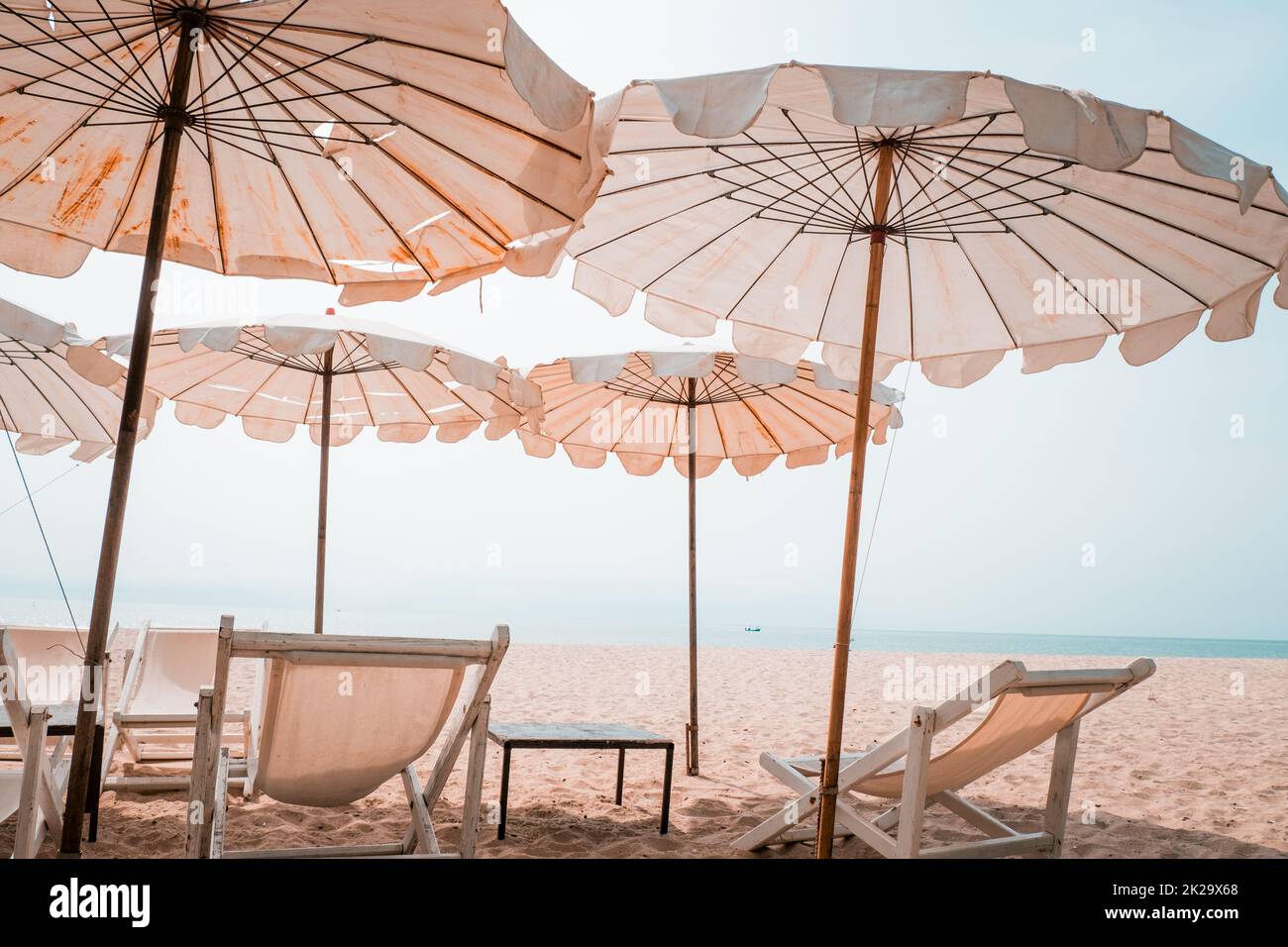 Liegestühle und weißer Sonnenschirm am Tropical Beach. Im Sommer weißer Sonnenschirm am Strand Stockfoto