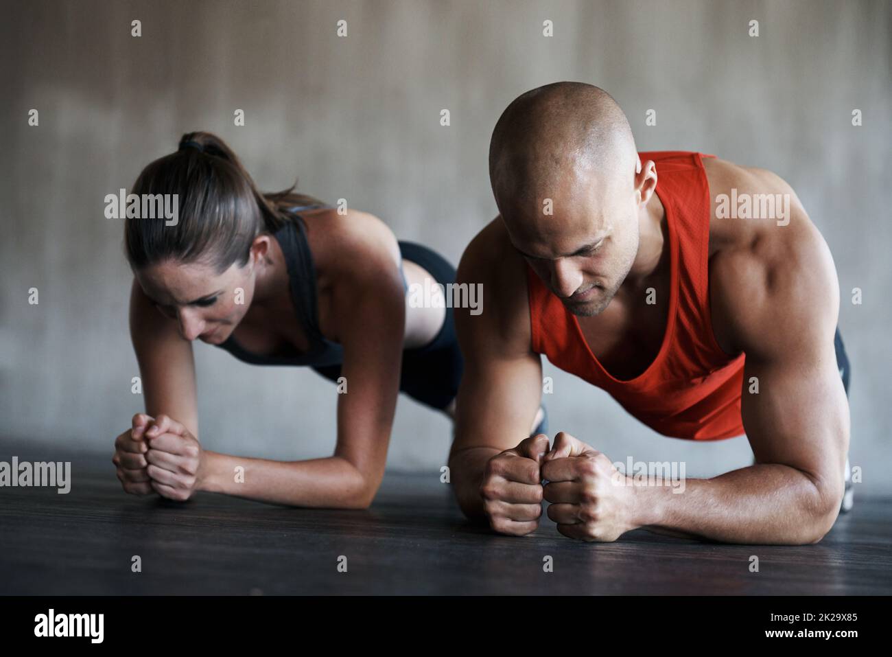 Drücke dich in die Fitness. Aufnahme eines Mannes und einer Frau, die im Fitnessstudio Plank-Übungen machen. Stockfoto