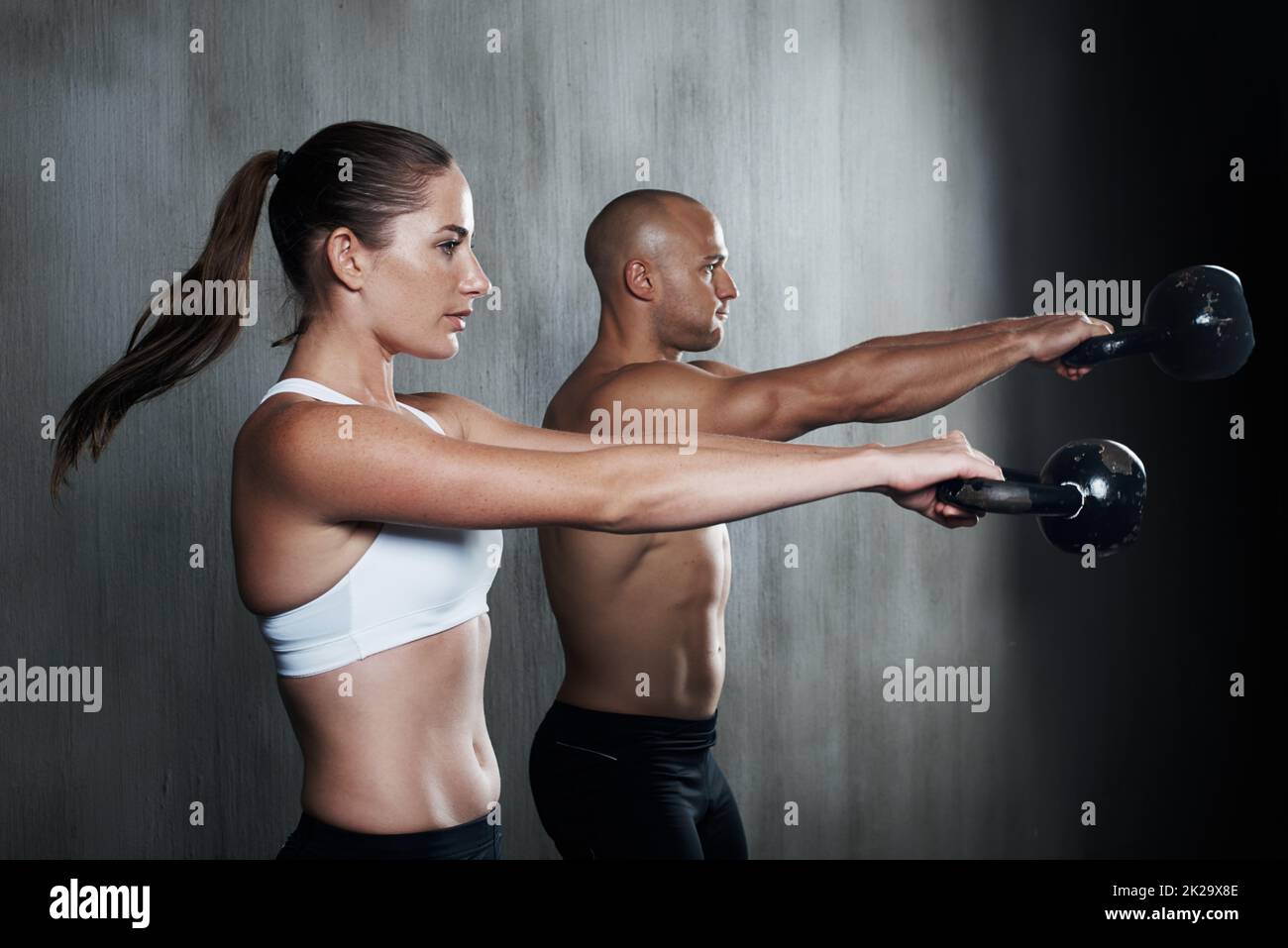 Training, um fit zu werden. Ein Mann und eine Frau trainieren mit den Kettelglocken im Fitnessstudio. Stockfoto
