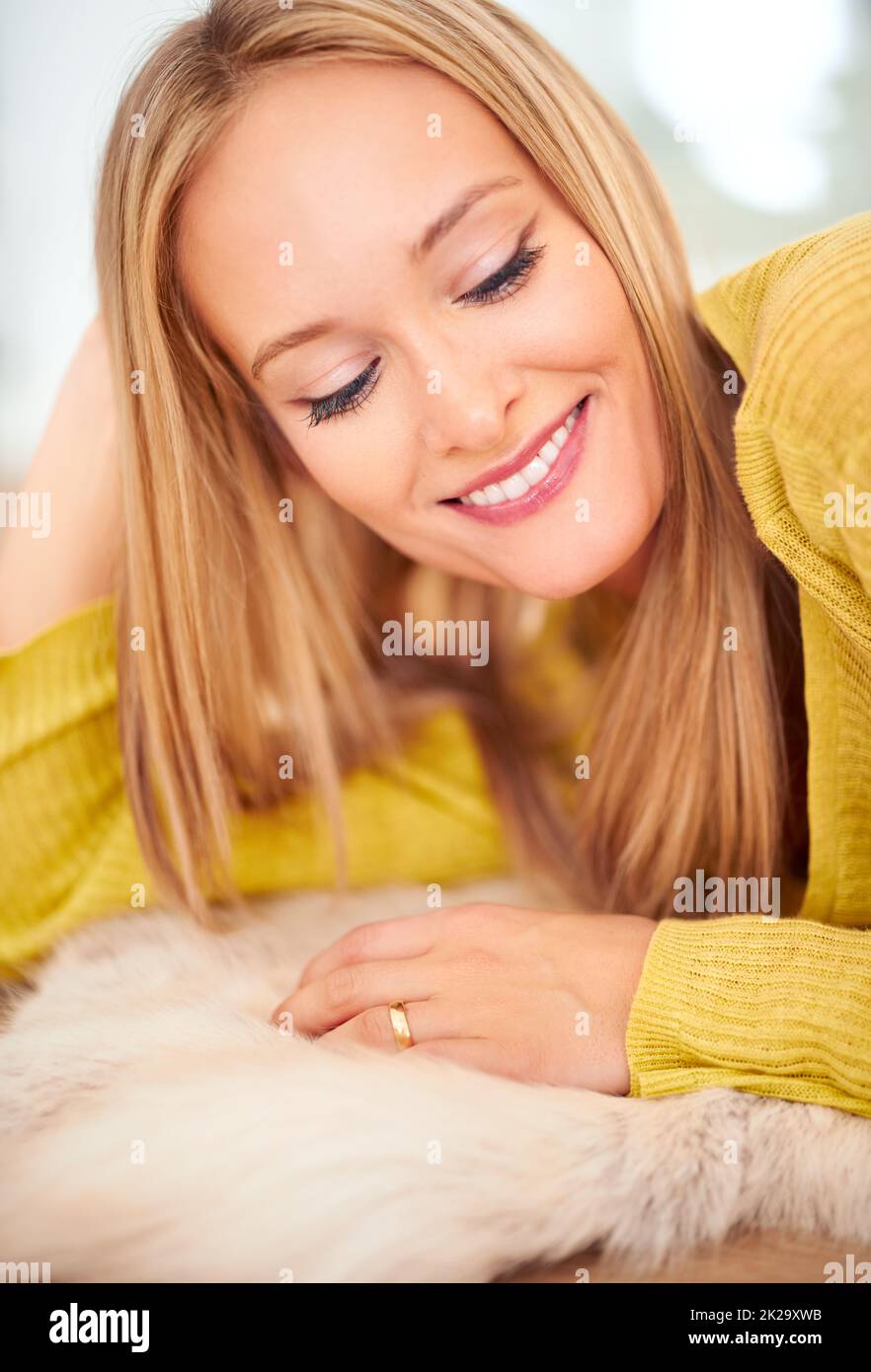 Ihr Lächeln ist eine Kurve, die alles gerade macht. Eine Frau, die bequem auf dem Boden in ihrem Haus liegt. Stockfoto
