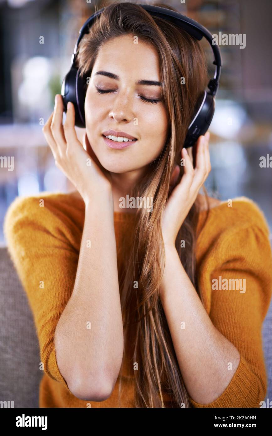 Es ist eine dieser entspannten Wiedergabelisten. Schöne junge Frau, die zu Hause Musik hört. Stockfoto