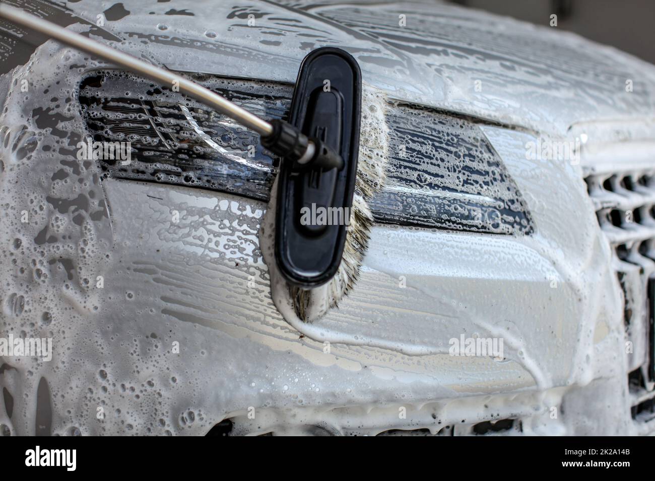 Frontscheinwerfer in Self-Service-Autowaschanlage gewaschen. Bürste aus Anschläge in Shampoo und Schaum. Stockfoto