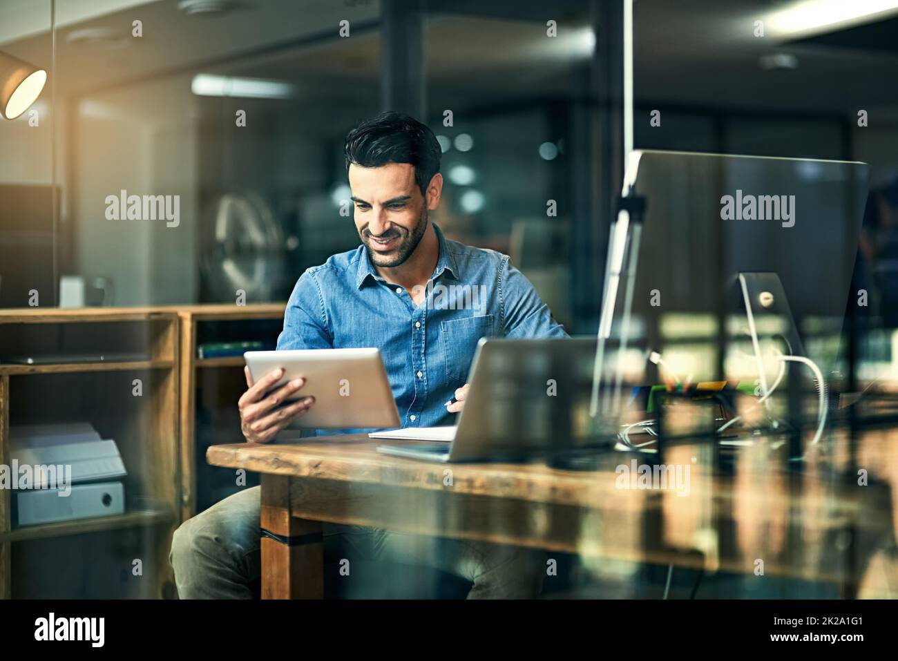 Technologie - ein Unternehmer bester Freund. Aufnahme eines jungen Geschäftsmannes, der ein digitales Tablet während einer späten Nacht auf der Arbeit benutzte. Stockfoto