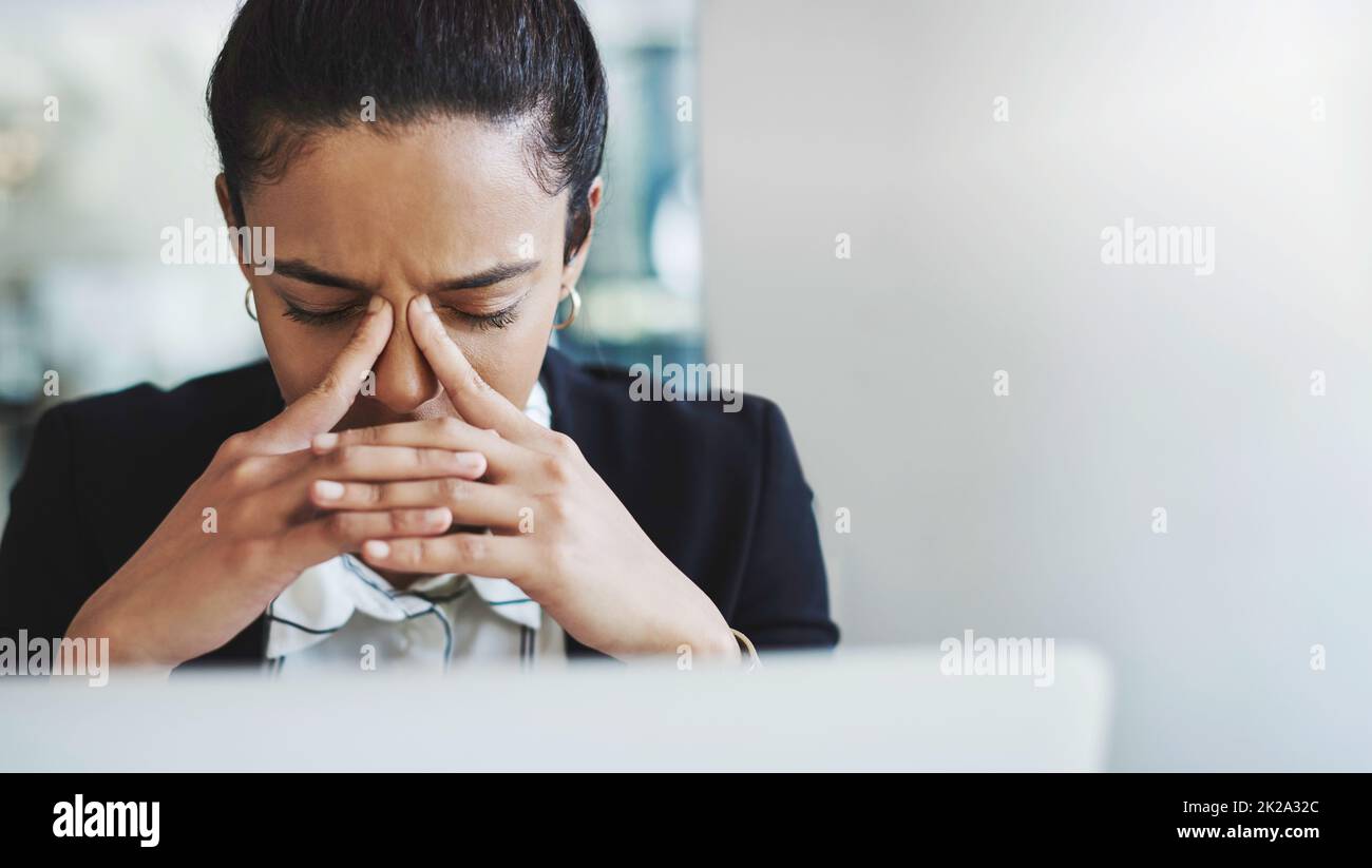 Es ist zu viel für eine Person, um damit umzugehen. Aufnahme einer jungen Geschäftsfrau, die gestresst aussieht, während sie an ihrem Schreibtisch in einem modernen Büro arbeitet. Stockfoto