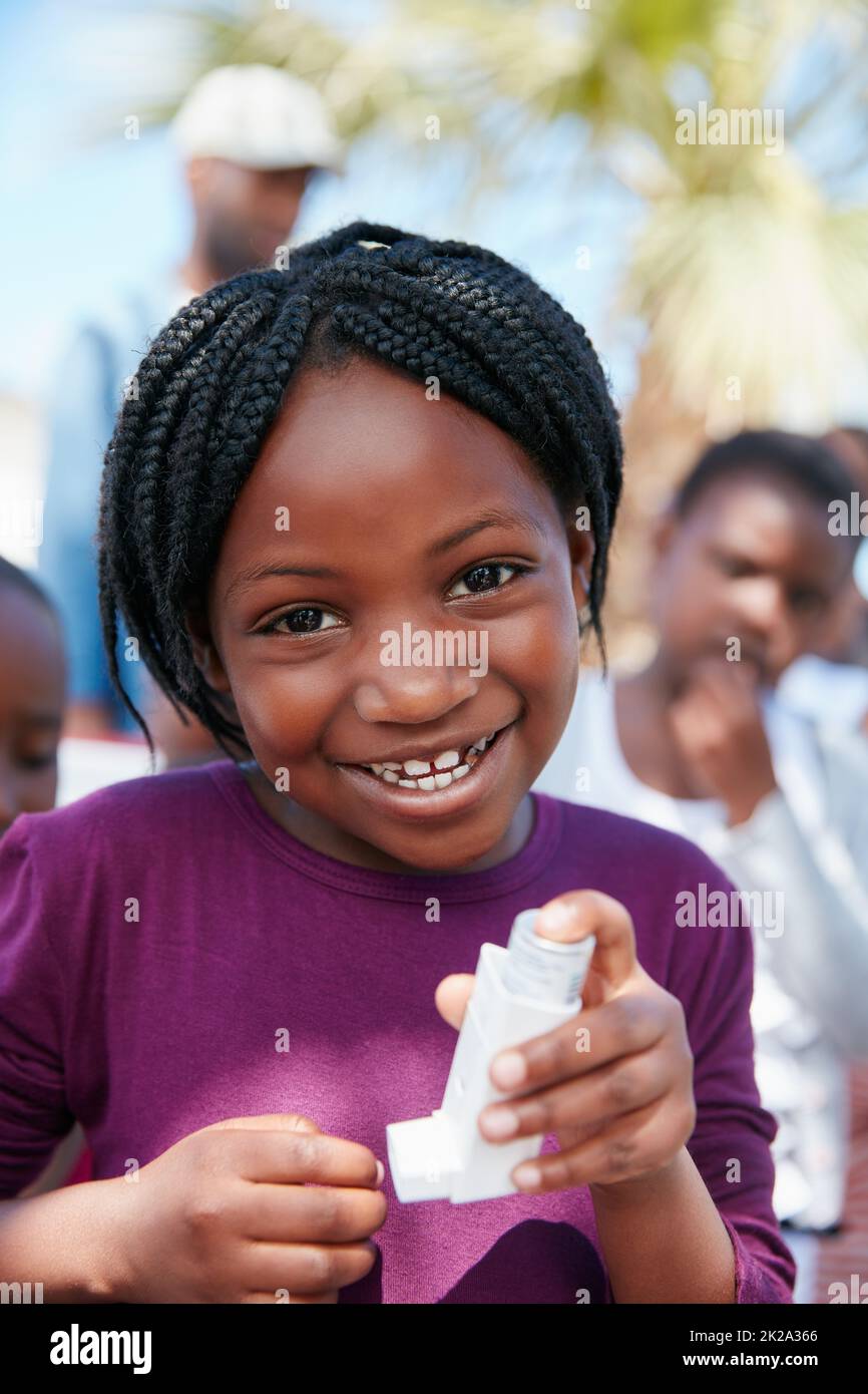 Ich kann jetzt leicht atmen. Porträt eines kleinen Mädchens, das einen Asthma-Inhalator bei einer Veranstaltung in der Gemeinde hält. Stockfoto