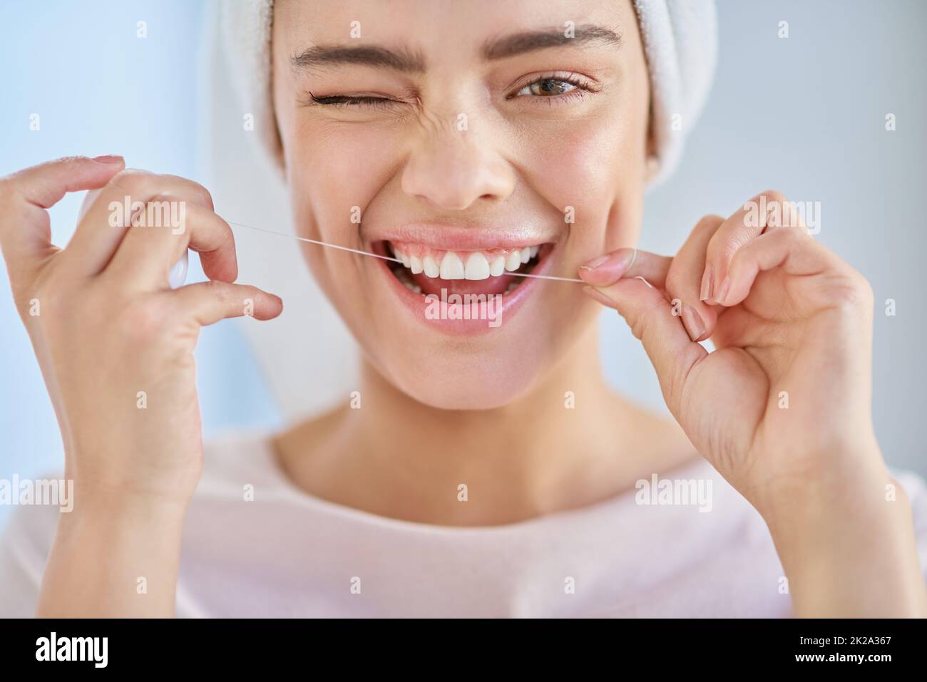 Vergessen Sie nicht, Zahnseide zu verwenden. Ein Porträt einer schönen jungen Frau, die zu Hause im Badezimmer ihre Zähne mit Zahnseide putzt. Stockfoto