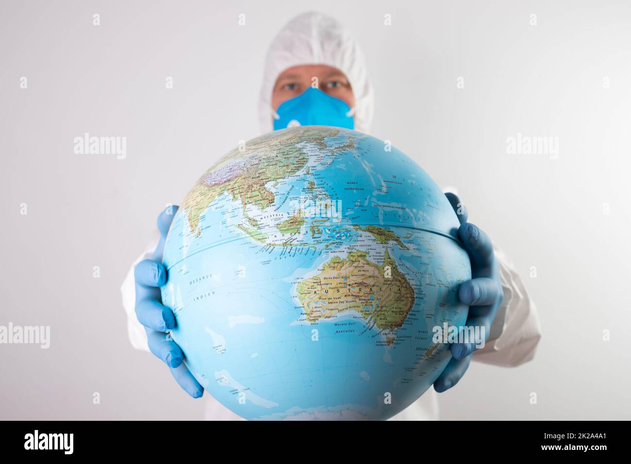 Ein Arzt hält den Planeten Erde in einer medizinischen Maske. Stockfoto