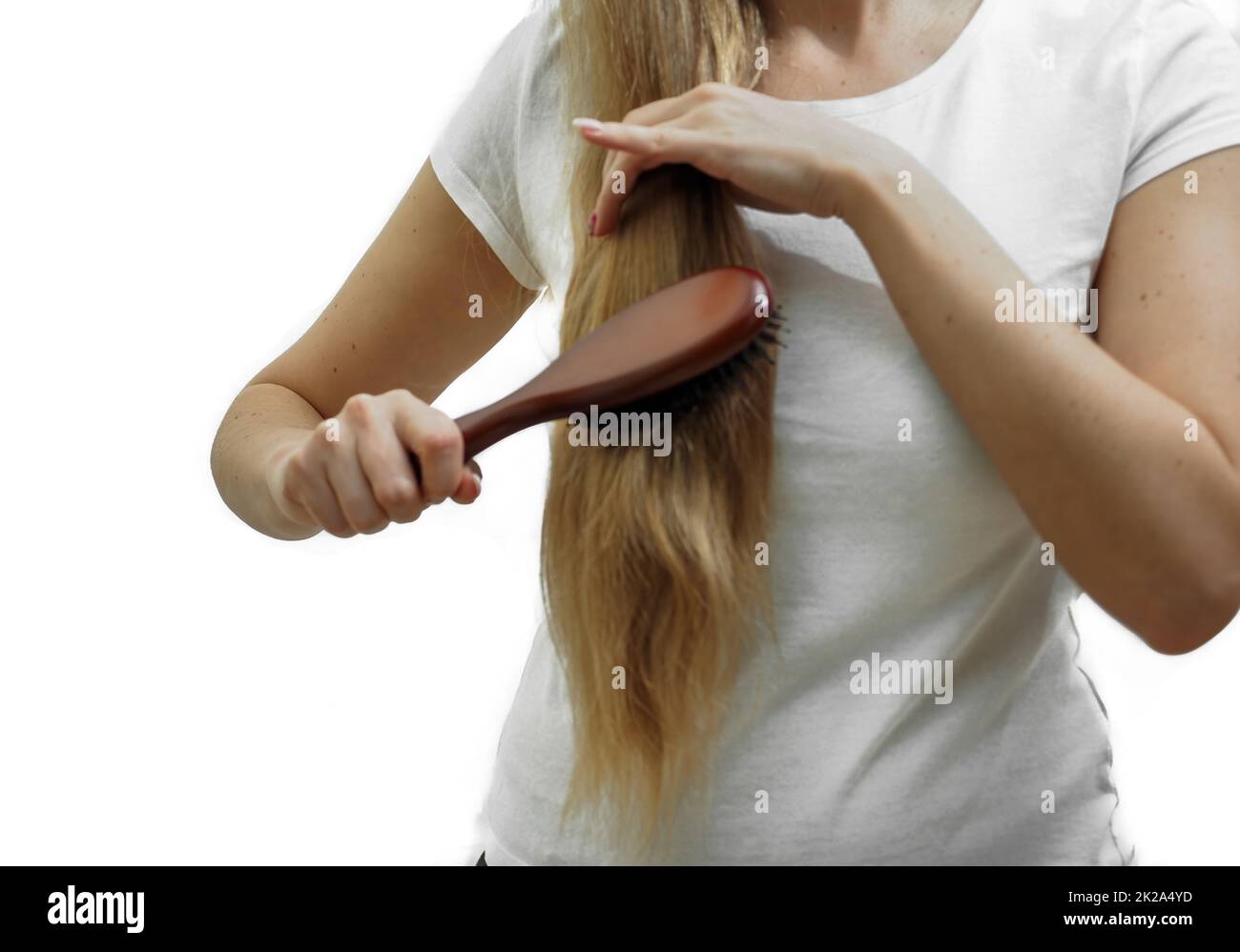 Ein Mädchen mit langen blonden Haaren kämmt sie mit einem Kamm. Das Problem von Haarausfall und Haarausfall, Haarpflege Stockfoto