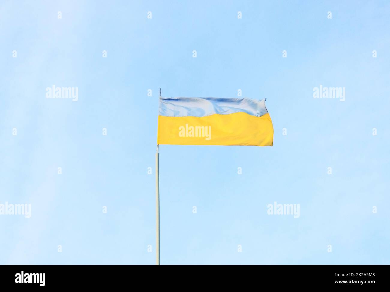 Ukrainische blaue und gelbe Flagge im Wind. Hintergrund von blauem Himmel und hellweißen Wolken. Die Staatsflagge der Ukraine Stockfoto