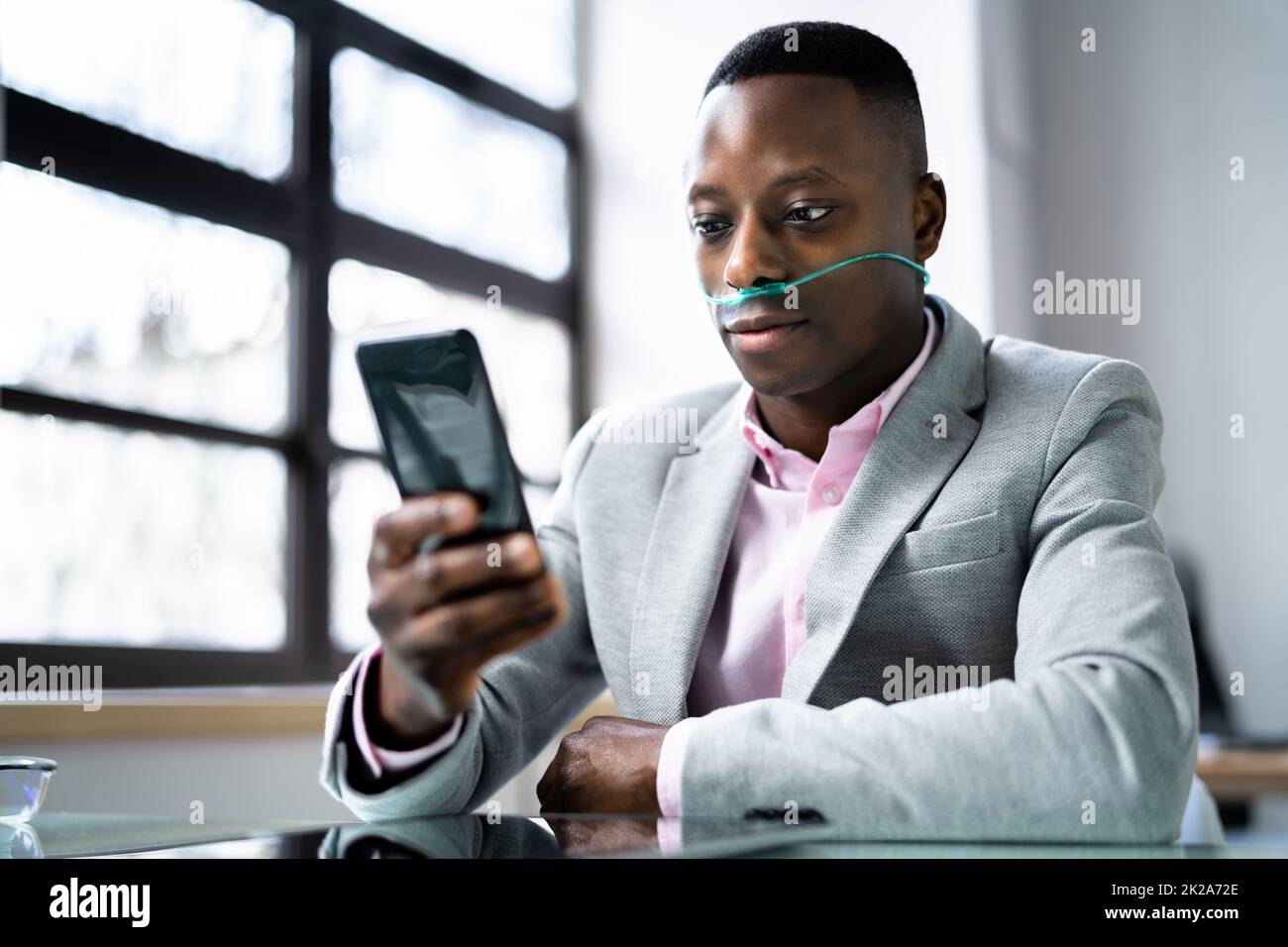 Afrikanischer Mann Mit Telefon Und Nasaler Sauerstoffsonde Stockfoto
