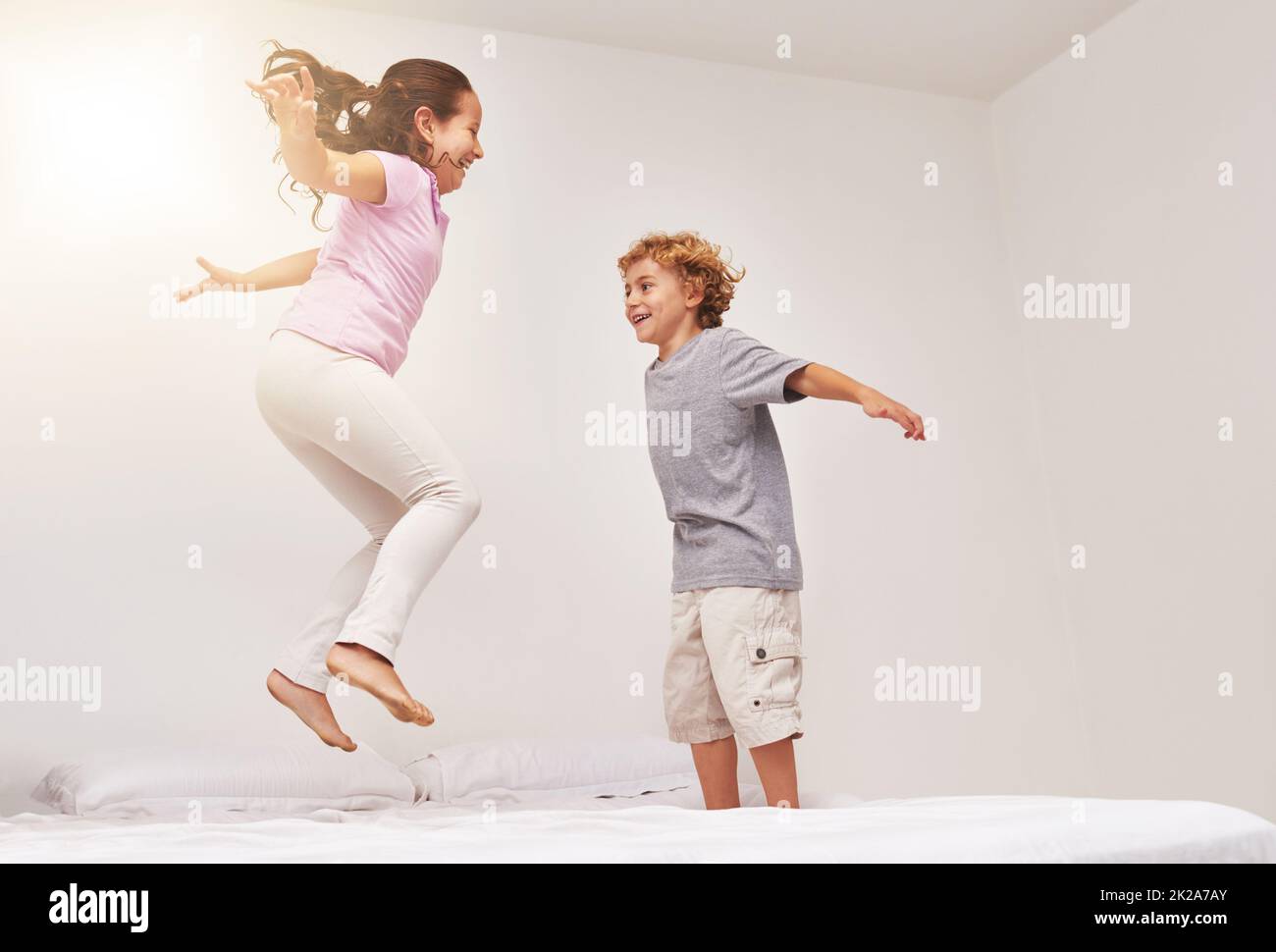 Wie hoch kannst du gehen. Aufnahme von zwei kleinen Kindern, die auf einem Bett springen. Stockfoto