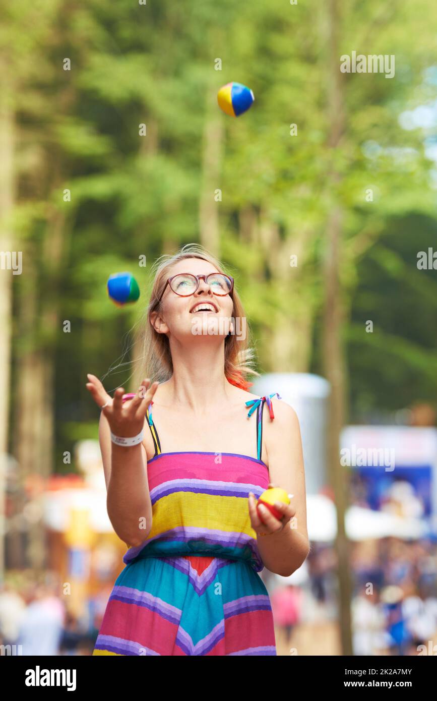 Ihre Jonglierkünste sind auf dem Ball. Aufnahme einer attraktiven jungen Frau, die auf einem Outdoor-Festival jongliert. Stockfoto