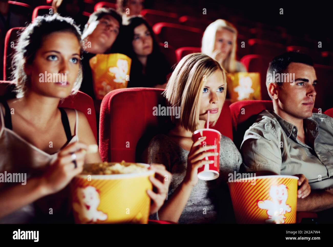 Süße Spannung. Freunde sitzen mit Erfrischungen und Popcorn und genießen gemeinsam einen Film. Stockfoto