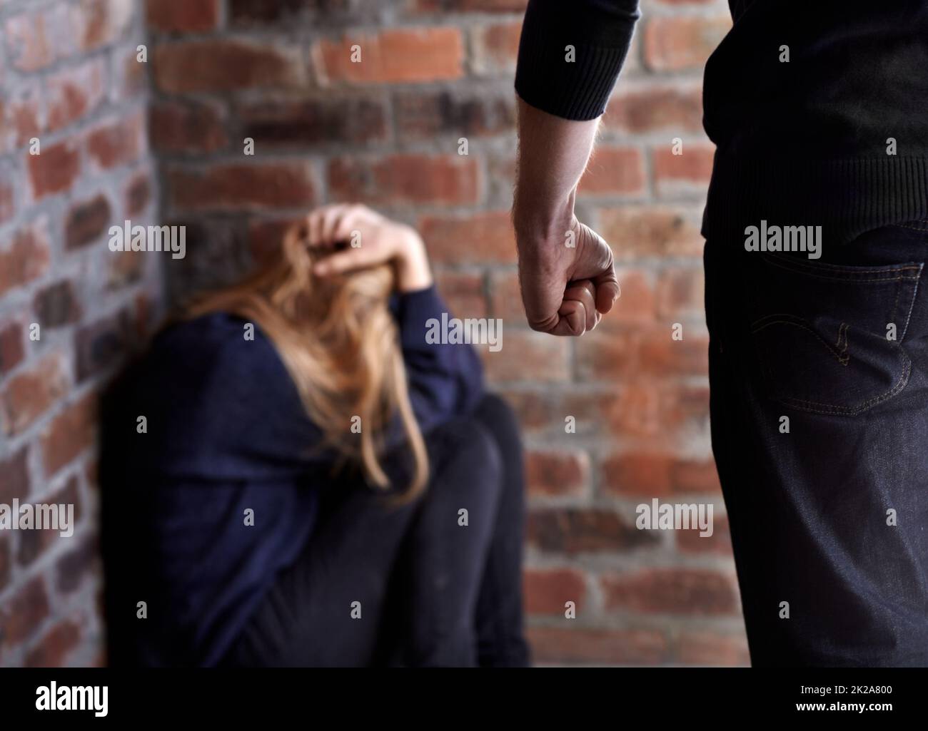Es wird versucht, sich zu verstecken. Missbraucht eine junge Frau mit ihren Händen im Haar, während ihr Abnutzer vor ihr steht. Stockfoto